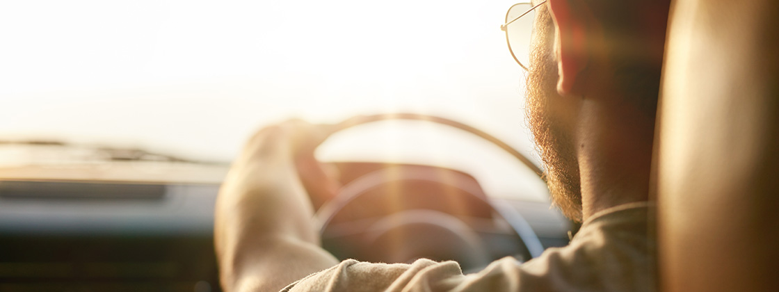 A woman stands beside her car with the hood open as steam rises from the engine block.