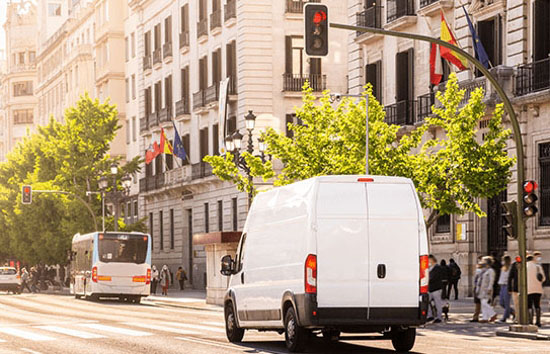White van traveling in a city downtown