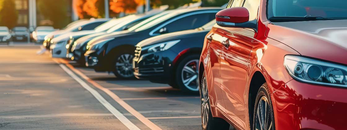 A row of cars parked in a lot, with one car facing forward