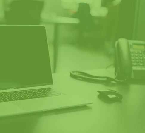 Shaded green image of phone and laptop on a desk