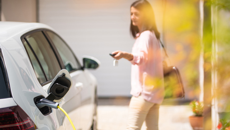 Woman charging car in driveway