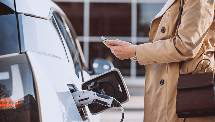 Woman in coat plugging in electric vehicle